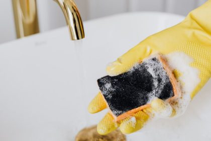 Mão segurando esponja de lavar vasilhas