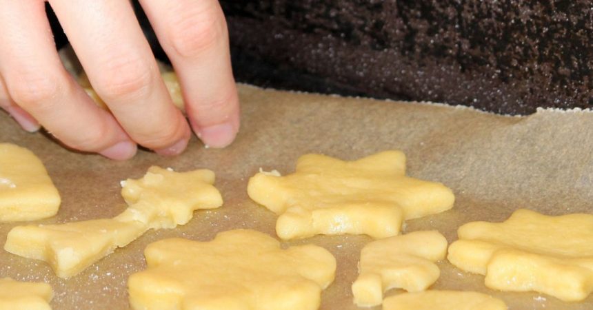 Mão colocando biscoitos em assadeira